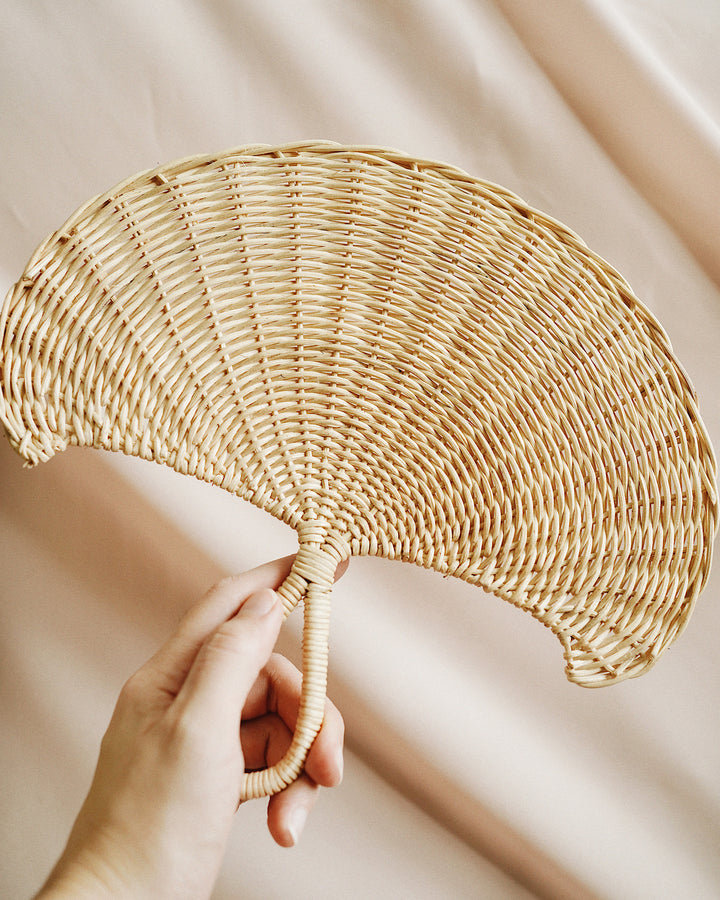 a hand holding rattan hand fan